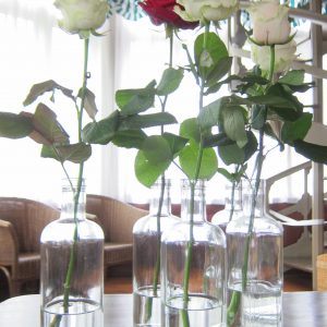Yksittäinen ruusu pullossa pöyäkoristeena